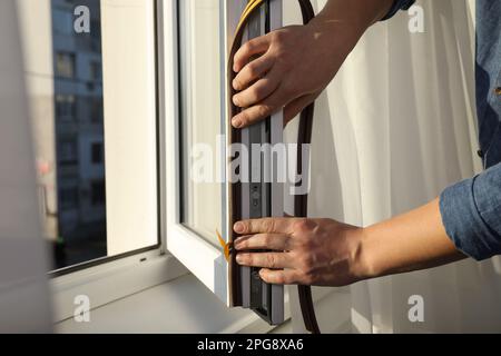 Construction worker putting sealing foam tape on window, closeup Stock Photo