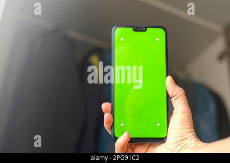 phone with Chroma Key Green Screen close-up. Buying Used Second Hand recycled clothes. Home sale. Recycling Eco New Life, European Store. Stock Photo