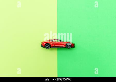 A red toy car isolated on two color background paper, after some edits. Stock Photo
