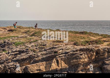 a couple walking along the rocks of the Sonabia cliff on the shore of the cantabrian sea, bay of biscay, cantabria, spain, europe Stock Photo