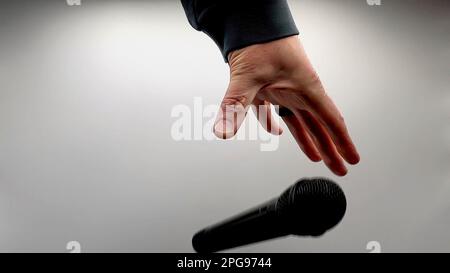 Caucasian Man Dropping the Mic Sequence - Popular Performance All Black Dynamic Microphone - Hands Only - White Background - Simple Concept Stock Photo