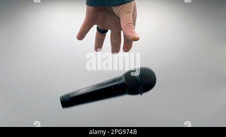 Caucasian Man Dropping the Mic Sequence - Popular Performance All Black Dynamic Microphone - Hands Only - White Background - Simple Concept Stock Photo