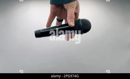 Caucasian Man Dropping the Mic Sequence - Popular Performance All Black Dynamic Microphone - Hands Only - White Background - Simple Concept Stock Photo