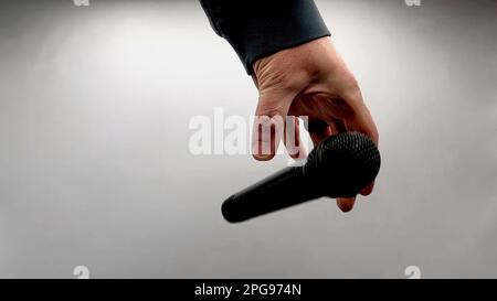 Caucasian Man Dropping the Mic Sequence - Popular Performance All Black Dynamic Microphone - Hands Only - White Background - Simple Concept Stock Photo