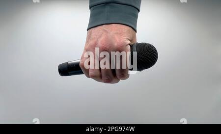 Caucasian Man Dropping the Mic Sequence - Popular Performance All Black Dynamic Microphone - Hands Only - White Background - Simple Concept Stock Photo