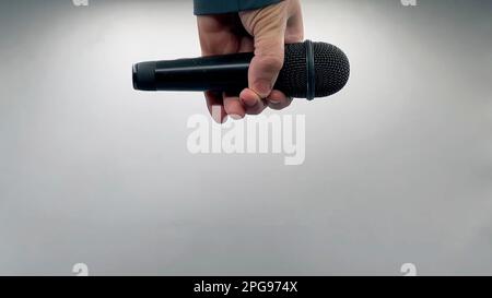 Caucasian Man Dropping the Mic Sequence - Popular Performance All Black Dynamic Microphone - Hands Only - White Background - Simple Concept Stock Photo