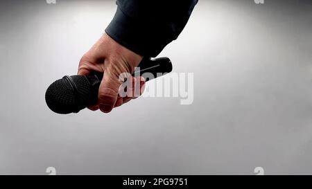 Caucasian Man Dropping the Mic Sequence - Popular Performance All Black Dynamic Microphone - Hands Only - White Background - Simple Concept Stock Photo