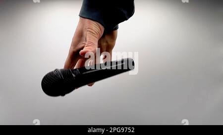 Caucasian Man Dropping the Mic Sequence - Popular Performance All Black Dynamic Microphone - Hands Only - White Background - Simple Concept Stock Photo