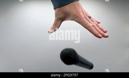 Caucasian Man Dropping the Mic Sequence - Popular Performance All Black Dynamic Microphone - Hands Only - White Background - Simple Concept Stock Photo