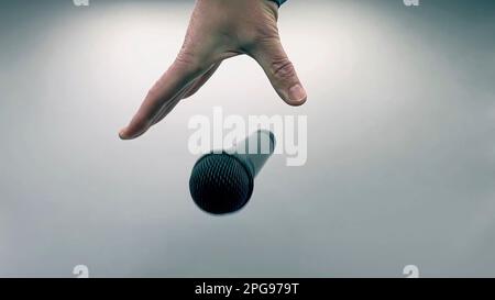 Caucasian Man Dropping the Mic Sequence - Popular Performance All Black Dynamic Microphone - Hands Only - White Background - Simple Concept Stock Photo