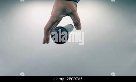 Caucasian Man Dropping the Mic Sequence - Popular Performance All Black Dynamic Microphone - Hands Only - White Background - Simple Concept Stock Photo