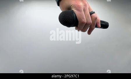 Caucasian Man Dropping the Mic Sequence - Popular Performance All Black Dynamic Microphone - Hands Only - White Background - Simple Concept Stock Photo