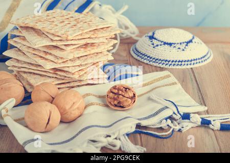 Passover celebration concept. Matzah, red kosher and walnut. Traditional ritual Jewish bread matzah, kippah and tallit on old wooden background. Passo Stock Photo