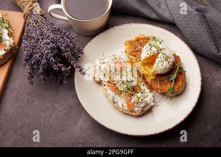 Aesthetic breakfast - sandwiches with eggs, salmon, alfalfa, chia seeds, sprouted peas, coffee cup. Lavender flowers cozy decorations Stock Photo