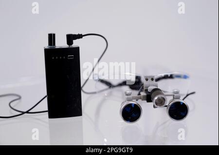 binoculars close-up on a white table dental appliances for treatment of gums teeth prosthetics filling canals magnification of the image for surgeon to work with instruments in surgical operations Stock Photo