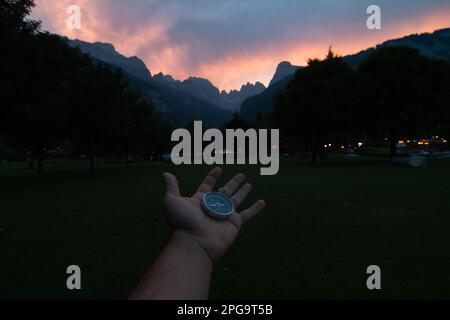 Compass held with one hand on a background mountain landscape. Concept of travel, freedom, lifestyle. Stock Photo