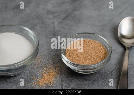 Dry yeast and sugar in a glass bowls close up on grey marble background, copy space. Baking process, ingredients for baking needs Stock Photo