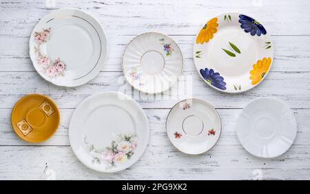 Assorted old vintage ceramic plates over white wooden table. Stock Photo