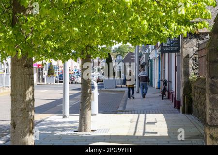 Two people walking in a street in the centre of Antrim Northern Ireland on a sunny spring day. Market Square Antrim Stock Photo