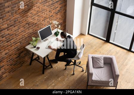 Focused young man using laptop, typing on keyboard, writing email or message, chatting, shopping, successful freelancer working online on computer. Stock Photo