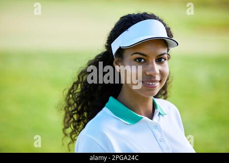 Portrait of smiling black woman playing golf outdoors and wearing activewear outfit Stock Photo