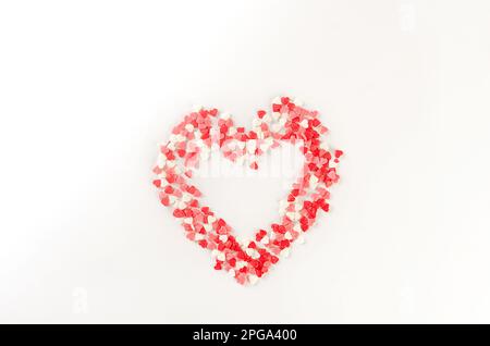 Colored sugar sprinkles in the shape of a heart. Sugar of red, pink and white sprinkle decoration for cake, sprinkles laid out in the shape heart Stock Photo