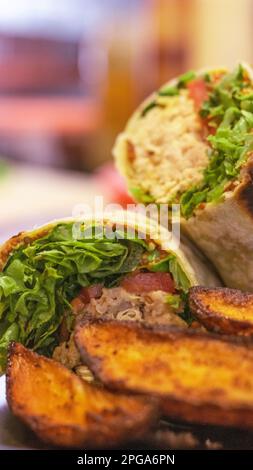 Wrap Burrito Shawarma served with french fries on dark plate. Blur background Stock Photo