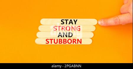 Stay strong and stubborn symbol. Concept words Stay strong and stubborn on wooden stick. Beautiful orange table orange background. Motivational busine Stock Photo