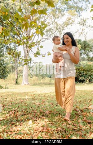 Latina mother holding a baby girl in her arms and walking in the countryside. Stock Photo