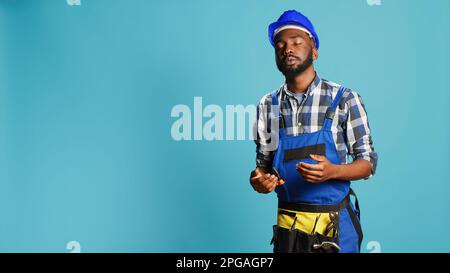 Dizzy construction worker feeling light headed in studio, almost fainting and having cartoonish stars above his head. Male contractor with hardhat being disoriented and unsteady, looney tunes. Stock Photo