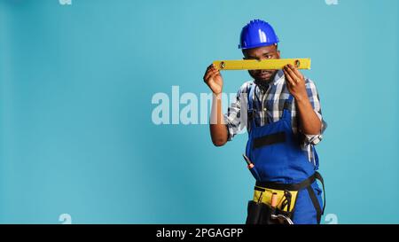 Young adult measuring surface with bench level tool, checking liquid in water level instrument in studio. Professional mechanic working with aligment equipment, construction balance. Stock Photo