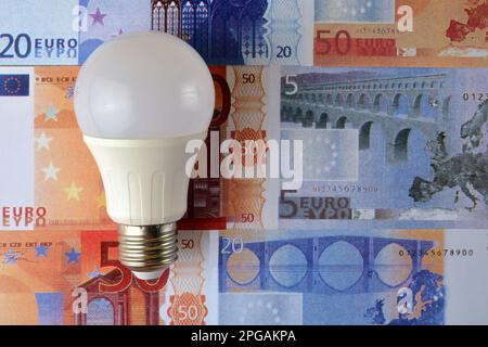 A low consumption led light bulb on a background of euro banknotes. Stock Photo