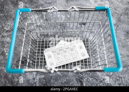 financial institution merging and holdings concept, bank made of paper inside of shopping basket ready to be bought by a competitor Stock Photo