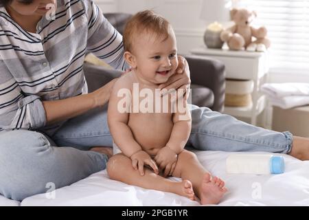 Mother applying dusting powder on her cute baby at home, closeup Stock Photo