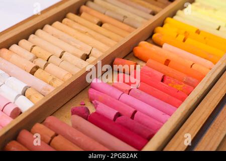 Set of soft pastels in wooden box as background, closeup. Drawing material Stock Photo