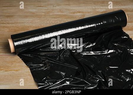 Roll of plastic stretch wrap film on wooden table Stock Photo