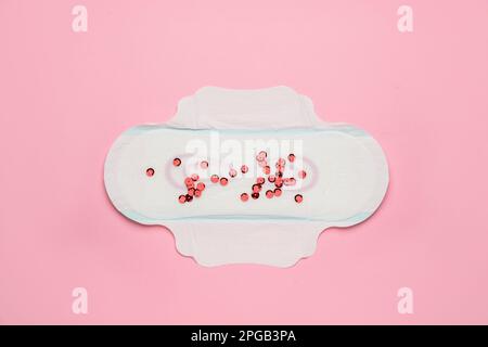 Menstrual pad with red sequins on white background, top view. Space for ...