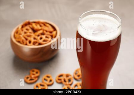 Beer and blurred bowl of pretzel crackers on background. Space for text Stock Photo
