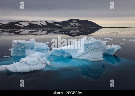Blue iceberg with reflections and visible ice underwater drifting in Hinlopen Strait, Spitsbergen, Svalbard Stock Photo