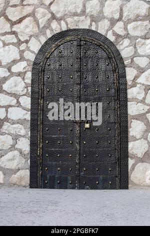 black vintage metal gate locked on a stone wall Stock Photo
