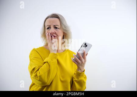 Caucasian businesswoman blonde lady woman hold mobile phone read unpleasant sms awful news feel indignant shocked. Bad notice from bank blocked account broken smartphone shock astonishment Stock Photo