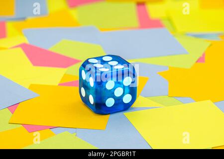 blue plastic dice on multicolored paper sticky notes  background Stock Photo