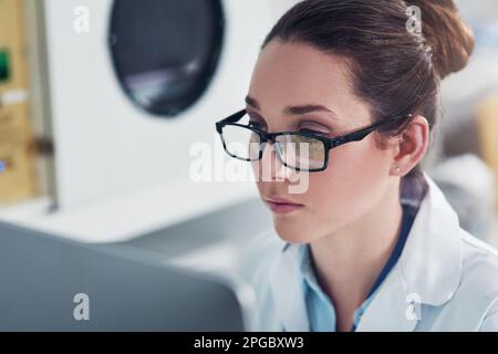 Everything seems to be in order. a focused young female scientist working on a computer inside of a laboratory during the day. Stock Photo