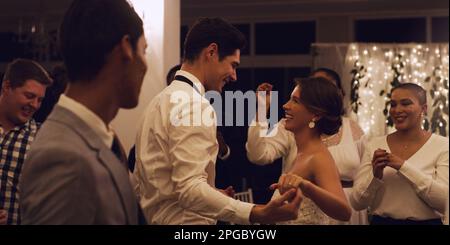 Dance always completes the celebration. an affectionate young newlywed couple dancing in front of their guests at their wedding reception. Stock Photo