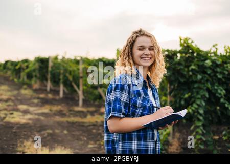 Farmer writing notes while spending time in her growing vines field. Business technology. People lifestyle. Farmer field. Stock Photo