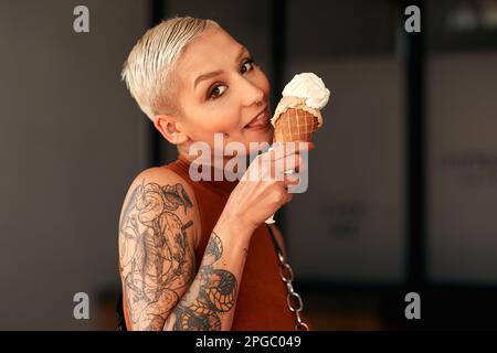 I just cant resist a good ice cream. a young woman enjoying a ice cream cone outdoors. Stock Photo