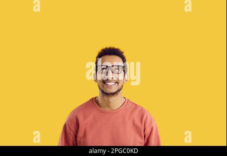 Studio portrait of a happy cheerful young black man in glasses looking up and smiling Stock Photo