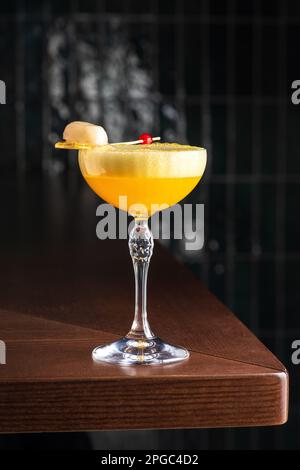 https://l450v.alamy.com/450v/2pgc4d2/delicious-light-yellow-sour-foam-cocktail-in-the-etched-glass-with-ice-and-d-red-flowers-for-decoration-dark-background-vertical-side-view-2pgc4d2.jpg