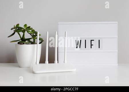 wifi connection concept - white router on table with green plant Stock Photo