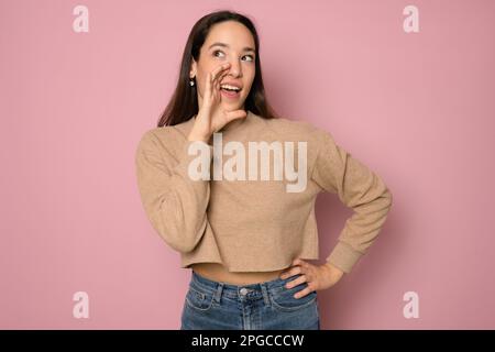 Photo of impressed young brunette lady say gossip wear casual sweater isolated on pink color background Stock Photo